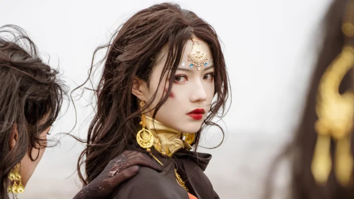 一名成年女性身穿深色服装并佩戴华丽金色饰品，回头望向镜头。