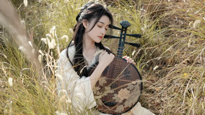 한 여성이 키 큰 풀밭에서 꽃무늬 비파를 안고 있다.