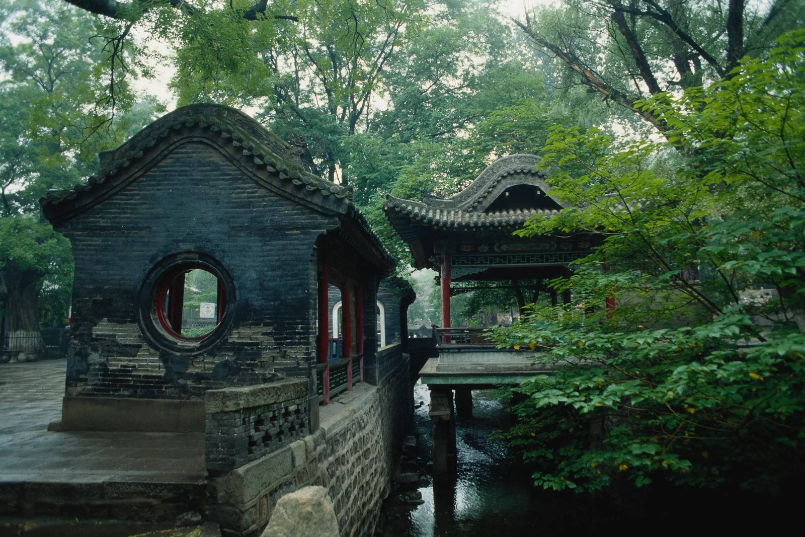 绿树掩映下的古建筑、亭桥与流水构成一幅幽静的园林景致。