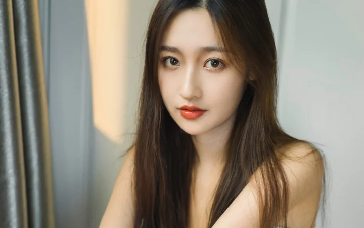 一位长发女性在室内近距离看向镜头。