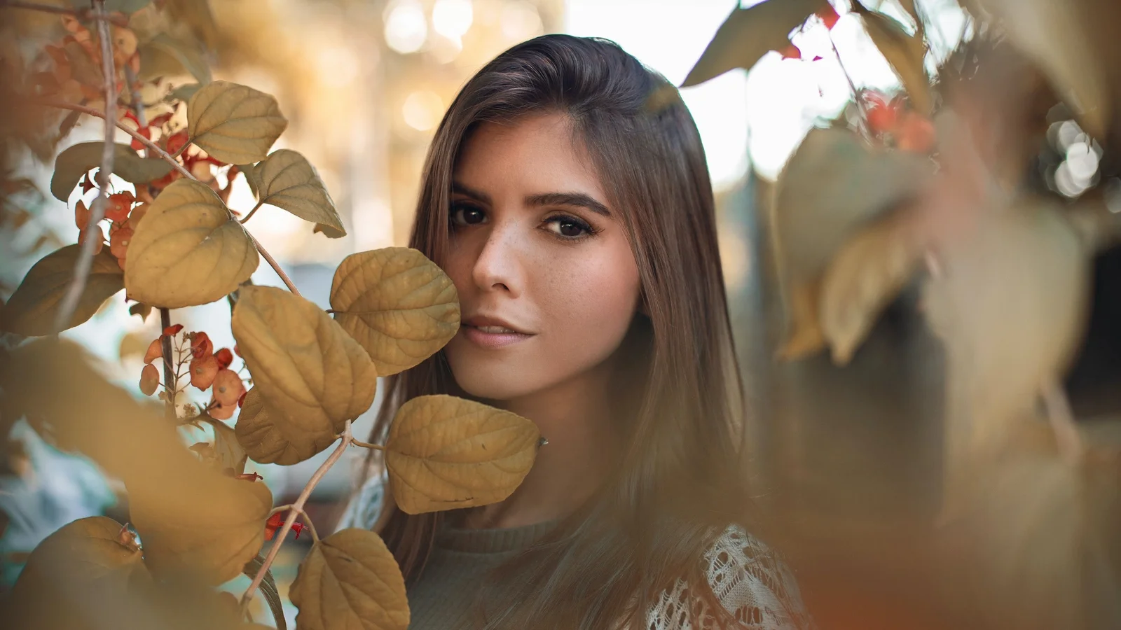 秋の葉と暖かなボケに囲まれた成人女性のポートレート。