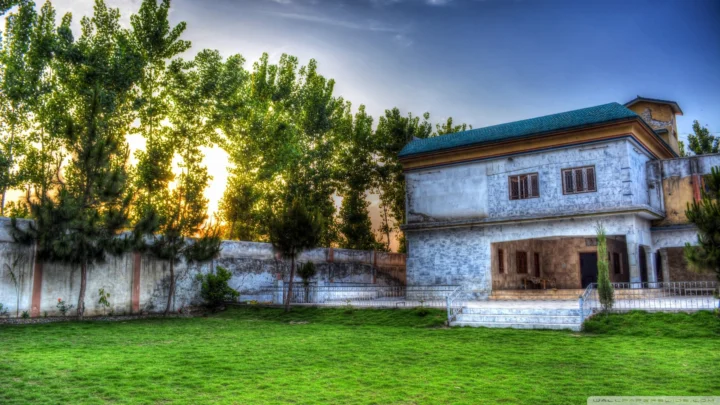 夕阳照耀着树木、草坪和一座带蓝色屋顶的庭院建筑。