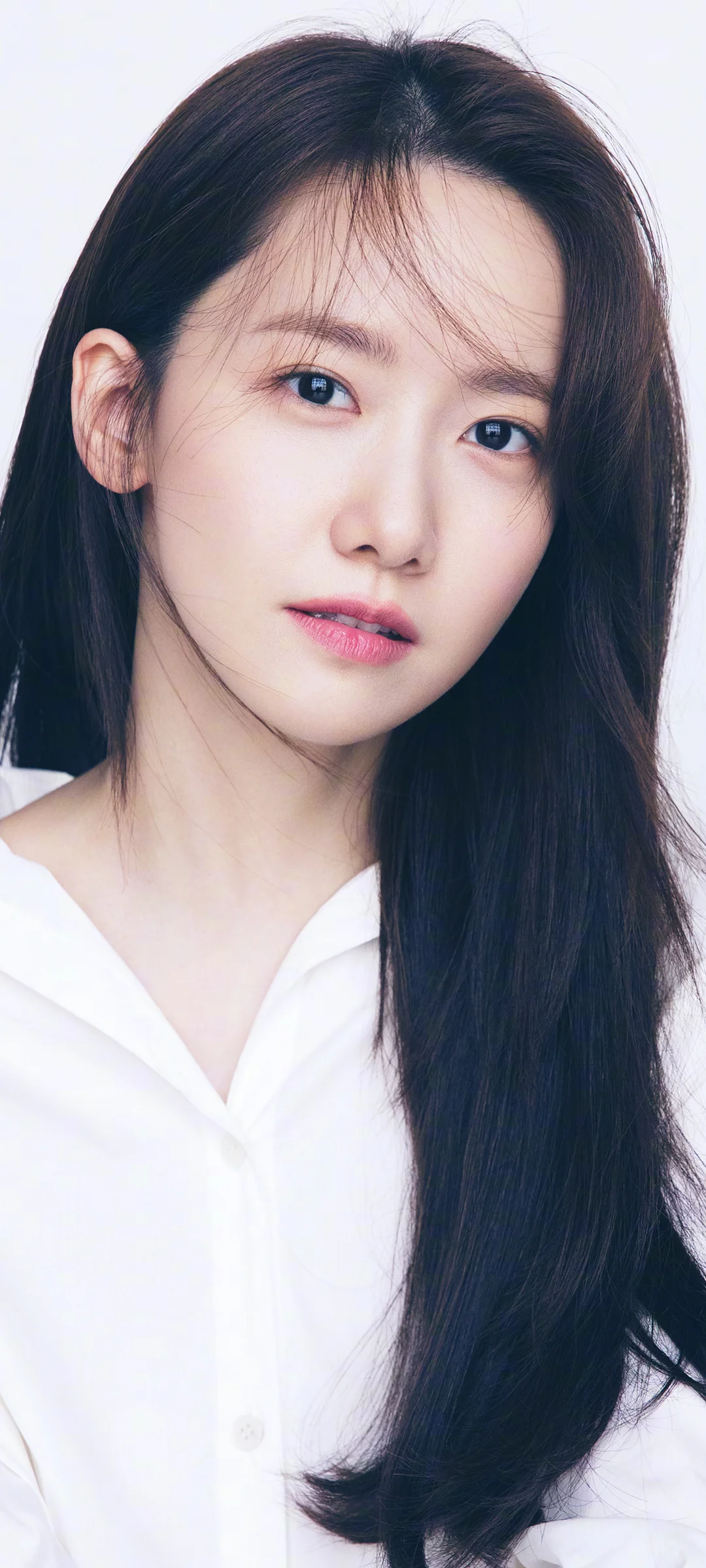 긴 검은 머리에 흰 셔츠를 입은 여성의 클로즈업 초상화입니다.