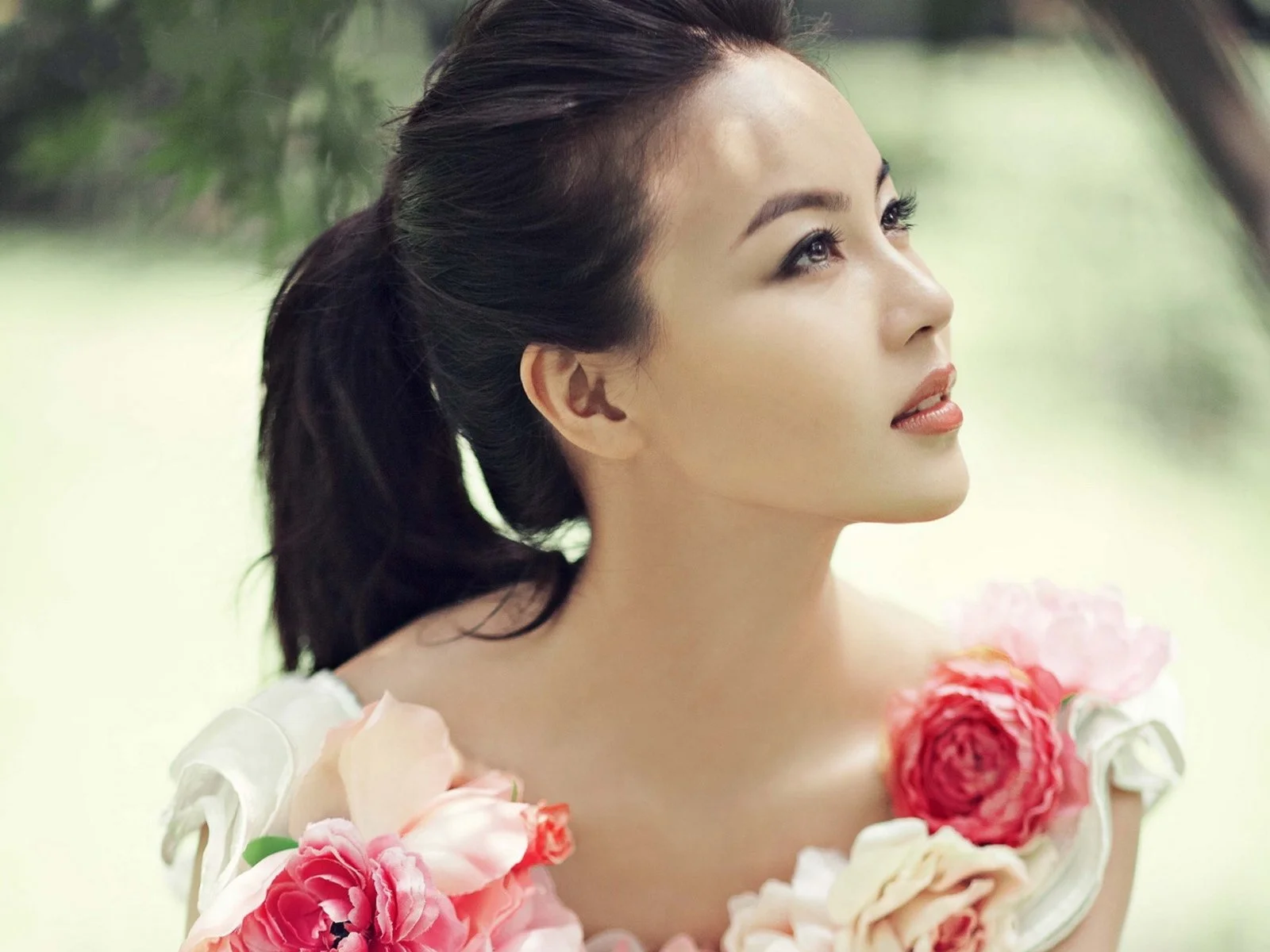 一名扎着马尾的女性抬头凝望，画面前景环绕着粉色和红色花朵。