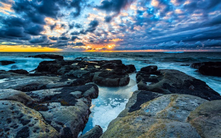 夕阳映照下的海岸岩石与翻涌海水构成壮丽的自然风景。