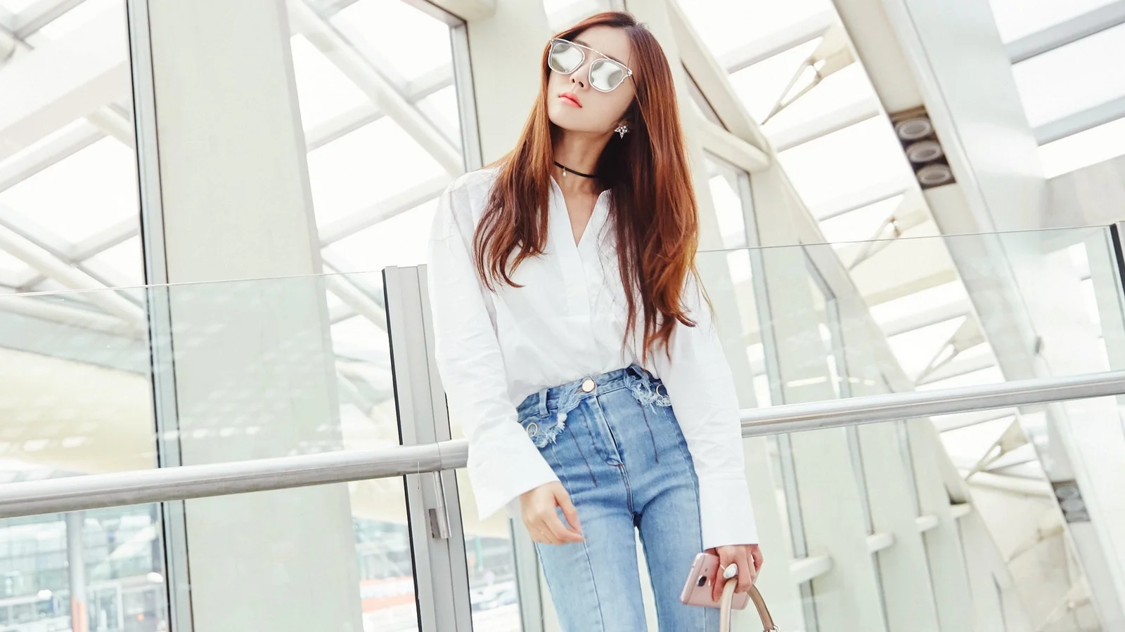 一名戴着太阳镜的成年女性站在明亮的玻璃建筑室内。