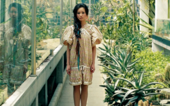 一名女子站在绿植环绕的玻璃温室通道中。
