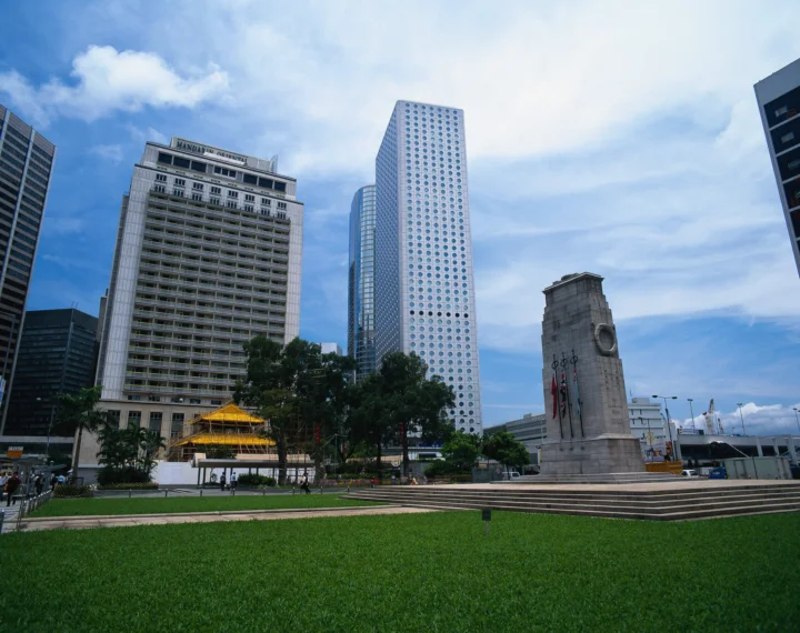 蓝天下的城市建筑、绿色草坪和纪念碑构成开阔的城市景观。