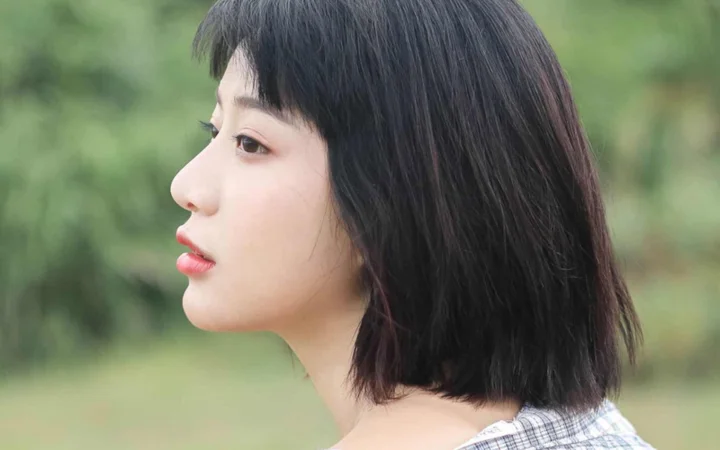 一位黑发女性在绿色虚化背景前呈现侧面肖像。