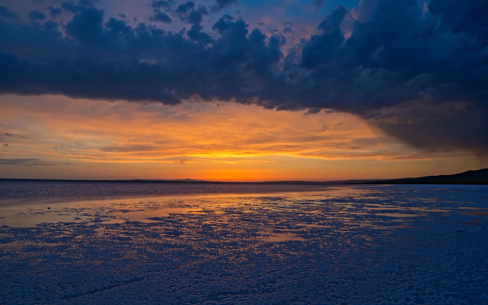 夕陽映照海面，厚重雲層鋪展在遠處的天空中。