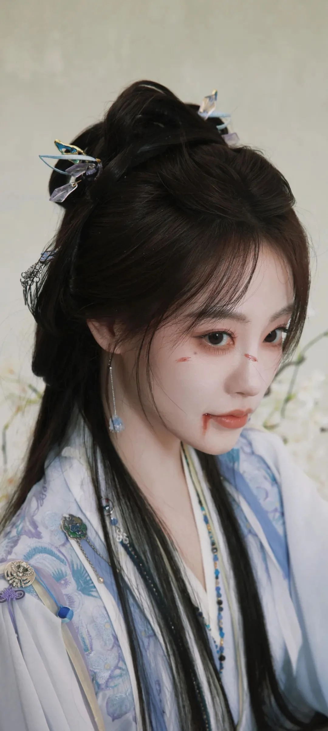 긴 머리의 여성이 밝은 색 전통 의상을 입고 옆모습을 보이며 머리에는 섬세한 비녀 장식이 꽂혀 있습니다.
