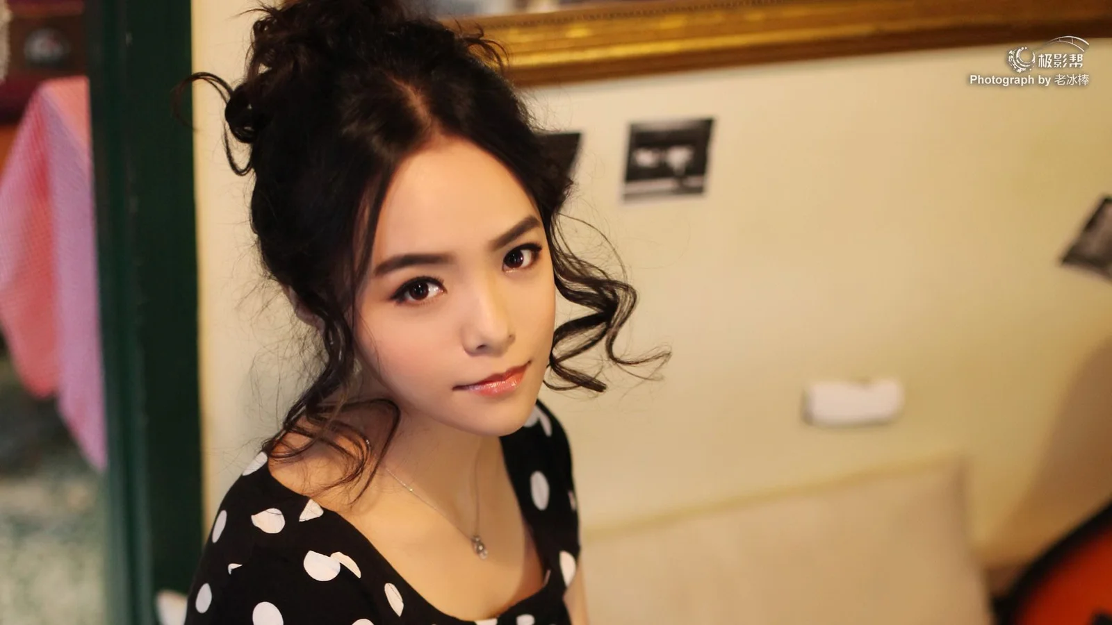 一名成年女性身穿黑白波點連衣裙，在室內面對鏡頭微笑。
