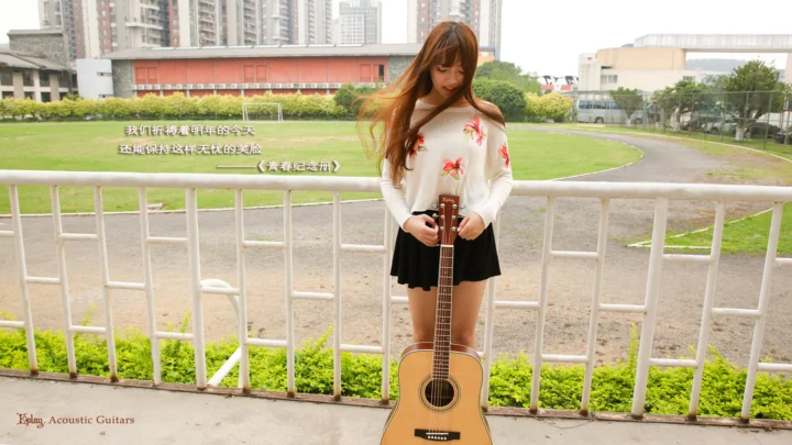 一名女性在运动场旁的栏杆前手持木吉他。