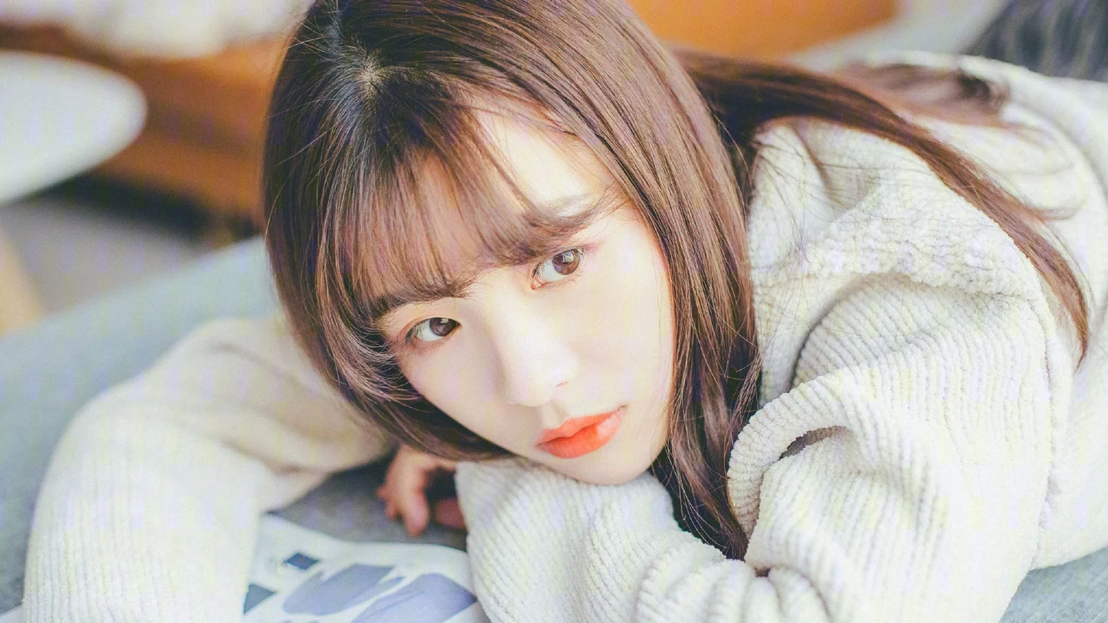 一名成年女子穿着浅色针织衫，将脸靠在手上看向镜头。