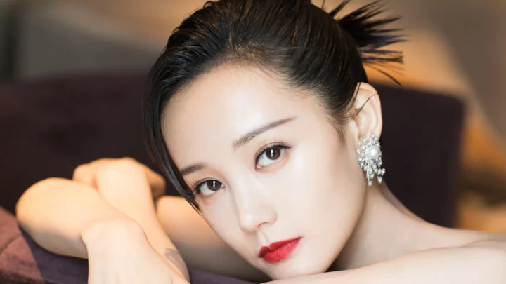 세련된 메이크업을 한 성인 여성이 소파에 기대어 카메라를 바라보고 있습니다.