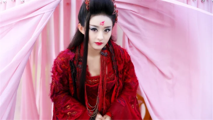 一名身穿红色传统服饰的女性坐在粉色帷幔前。