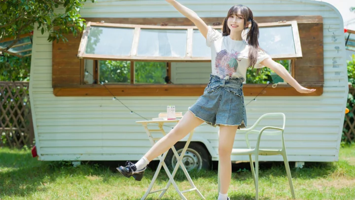 一名女子站在草地上的露营车前展开双臂。