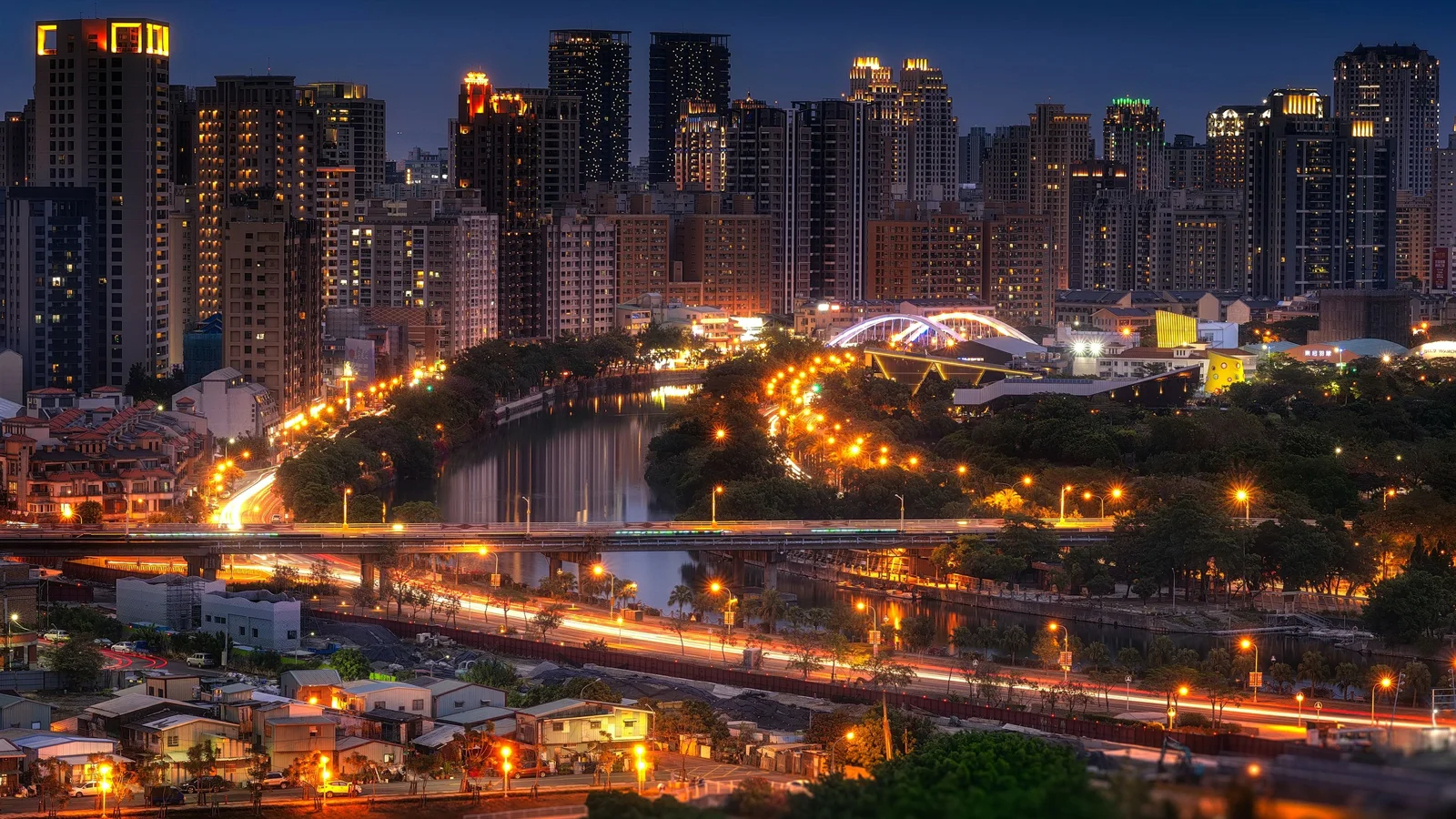 夜色中的城市天际线灯火通明，河流、桥梁和道路交织在高楼之间。