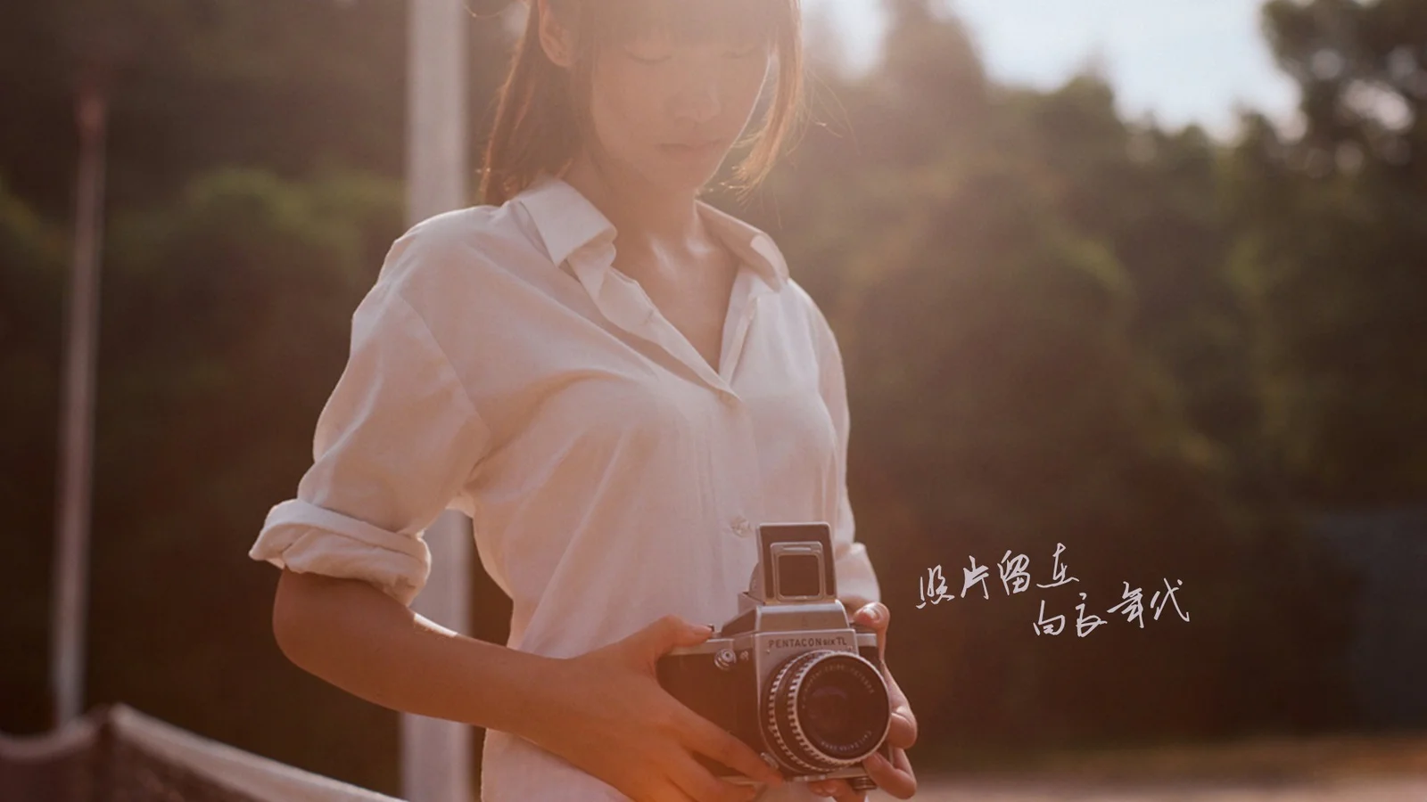 一名穿白衬衫的成年女性在户外暖色阳光下手持复古相机。