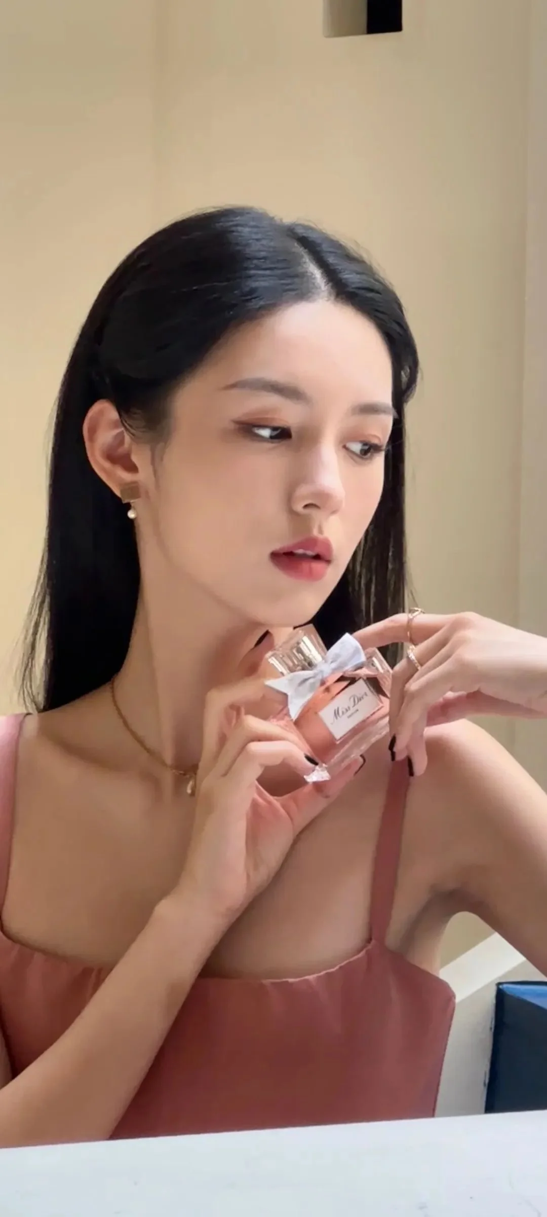一位成年女性在室内手持香水瓶的竖幅肖像照片。