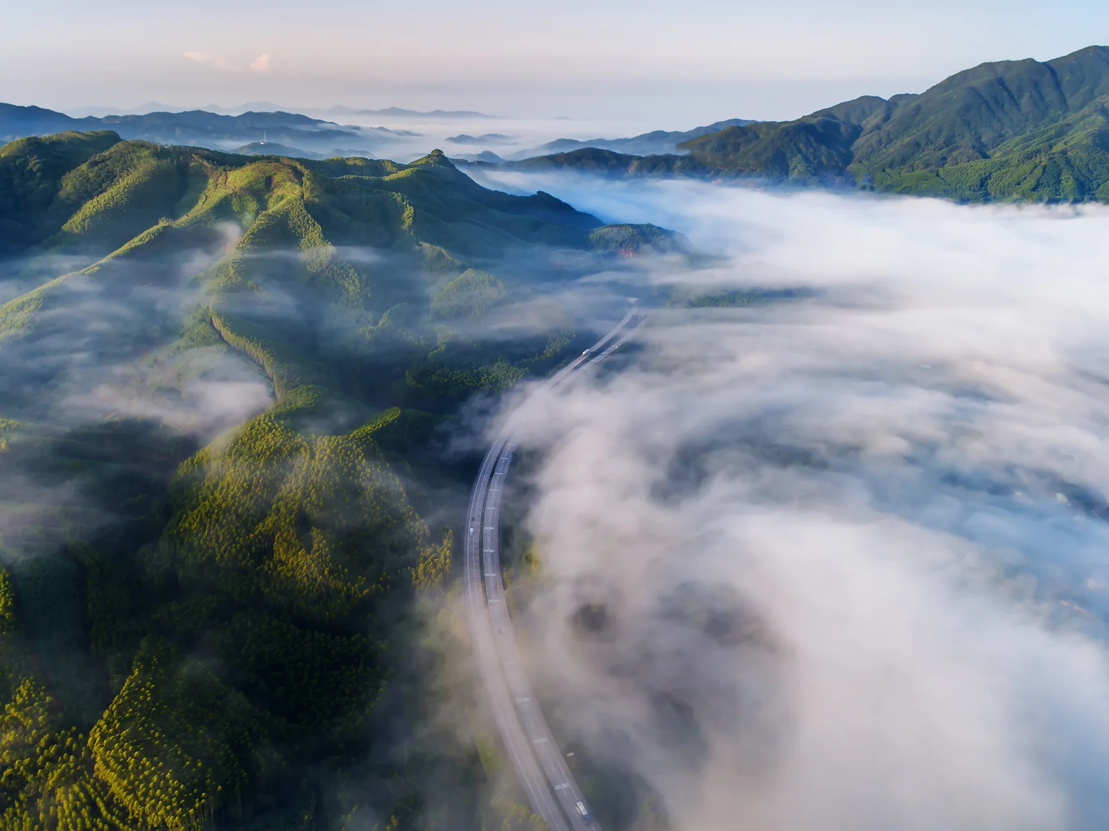 群山被雲霧環繞，一條蜿蜒公路穿行其間。