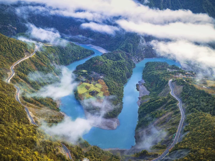 俯瞰云雾缭绕的山谷、蜿蜒河流、森林和山路。