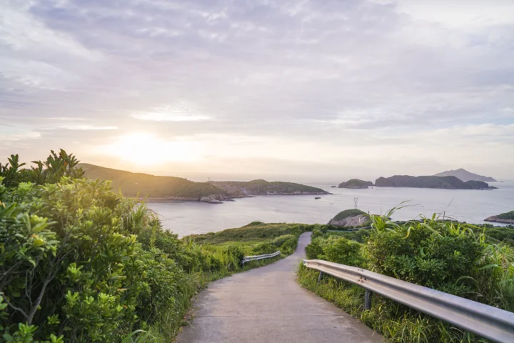 夕阳照耀着海岸、远处岛屿和通向海边的道路。