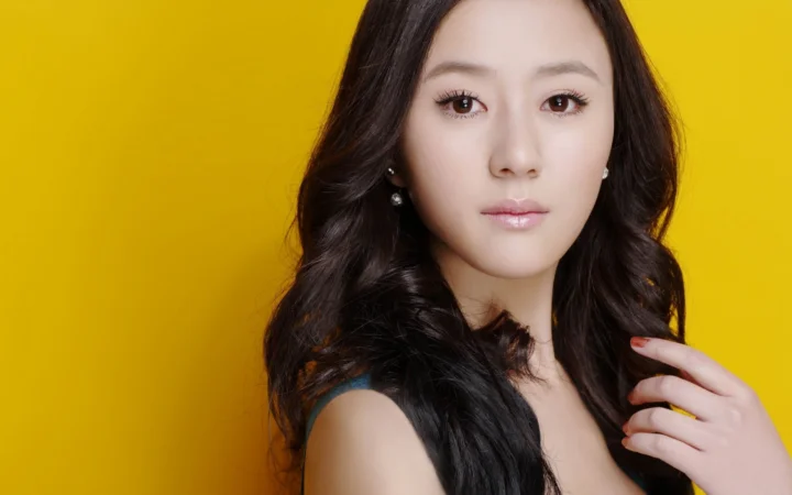 一名成年女性在明亮黄色背景前面对镜头摆姿势。