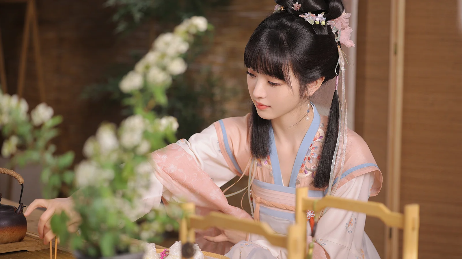 一名身穿传统服饰的女子坐在室内花卉旁。