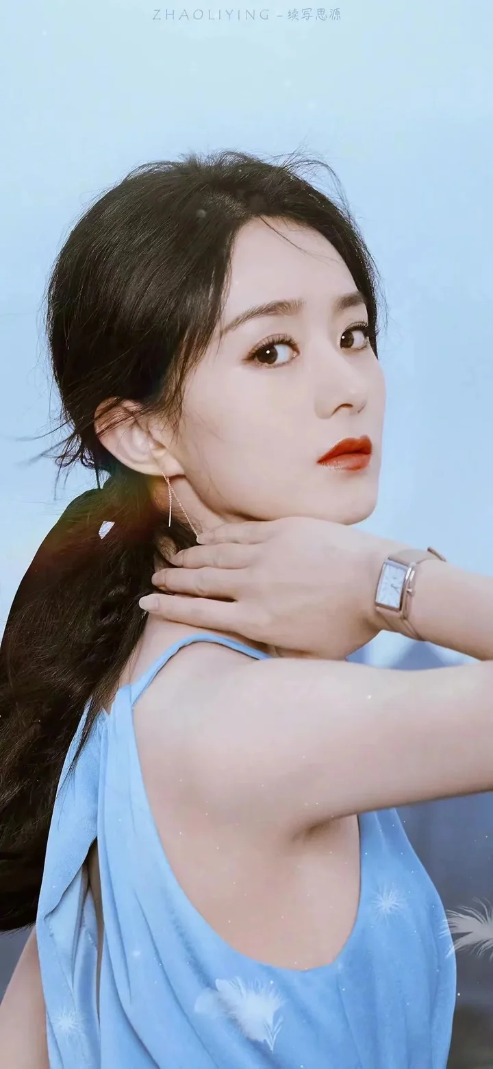 一名身穿浅蓝色无袖服装的女性在浅蓝色背景前回望镜头。