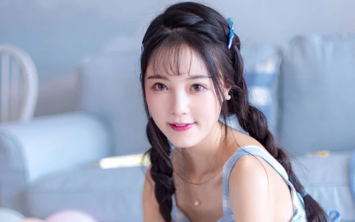 一位留着深色编发的女性在室内面对镜头微笑。
