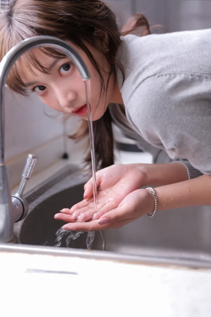 一名女性在水槽前用流动的水洗手。