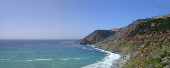 湛蓝海水沿着陡峭的海岸悬崖延伸，白色浪花拍打着岸边。