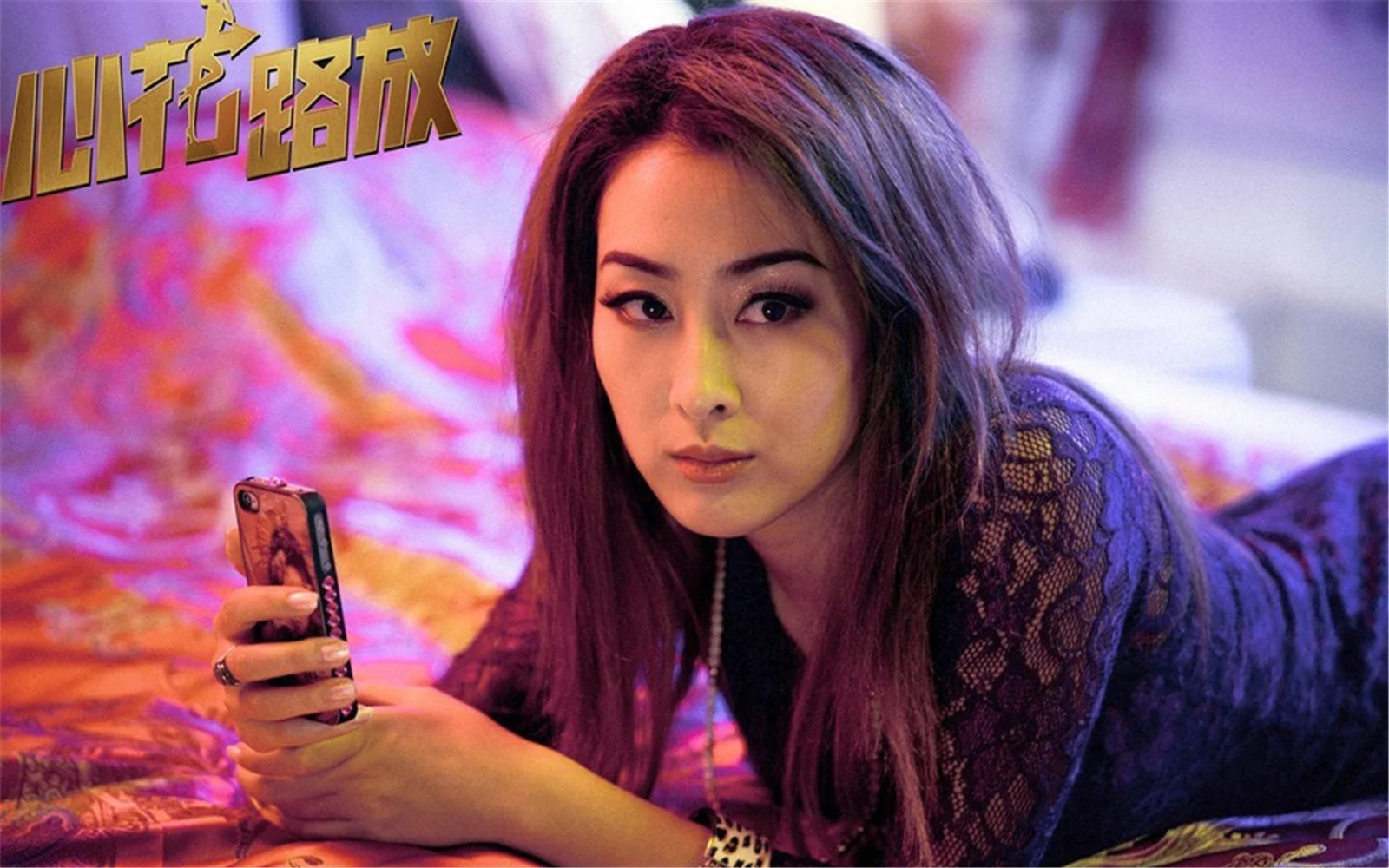 一名成年女子在彩色燈光下手持智慧型手機面對鏡頭。
