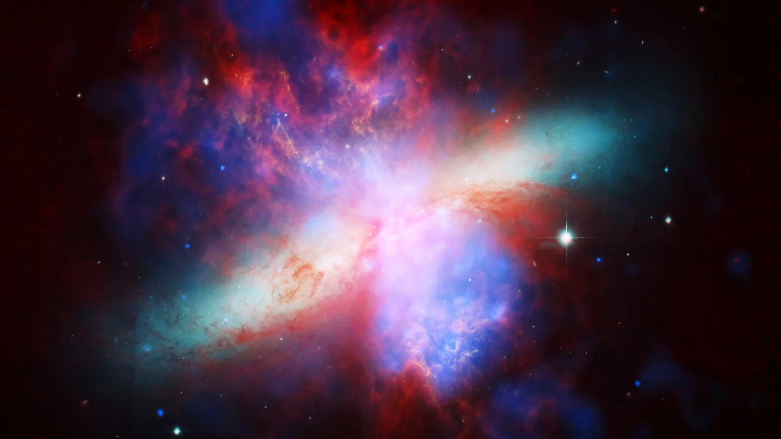 赤、青、紫が交差する鮮やかな星雲と銀河のような構造に、明るい星々が散らばっています。