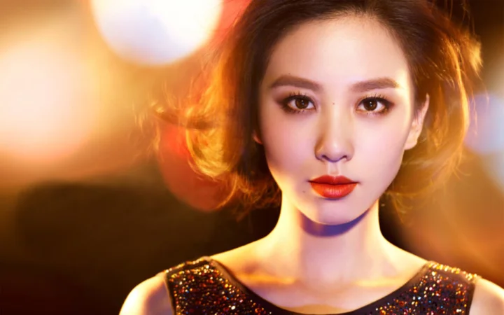 따뜻한 보케 조명을 배경으로 한 성인 여성의 정면 인물 사진.