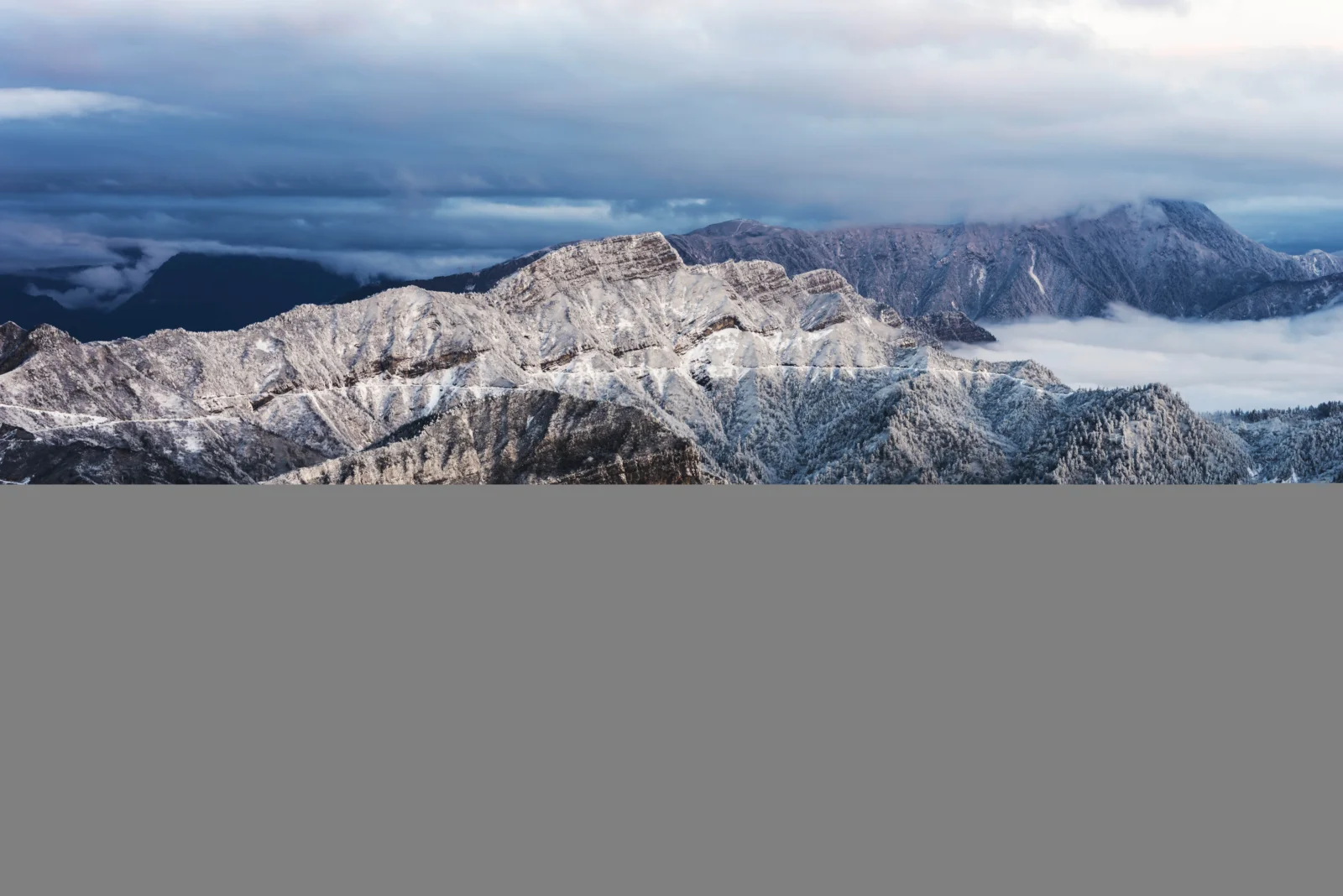 画面展现了覆雪山脉、低垂云层与阴郁蓝色天空。
