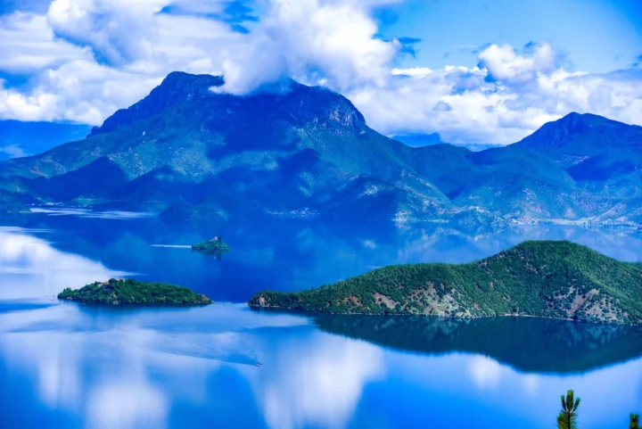 蓝色湖面映照着群山、云朵和湖中的绿色岛屿。