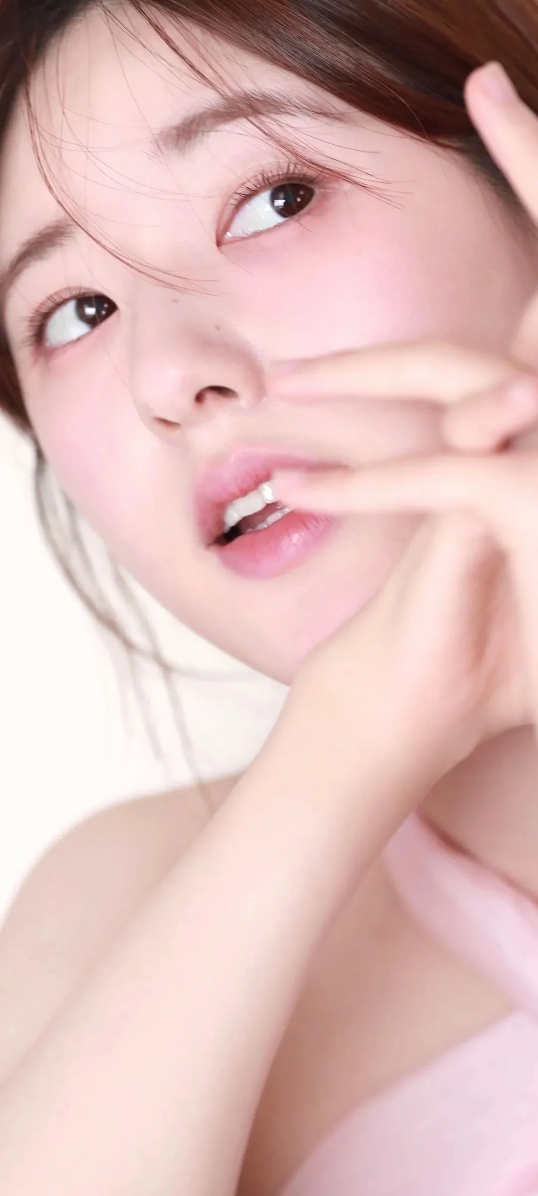 一位女性的柔光面部特写，手指轻触脸颊，背景简洁明亮。