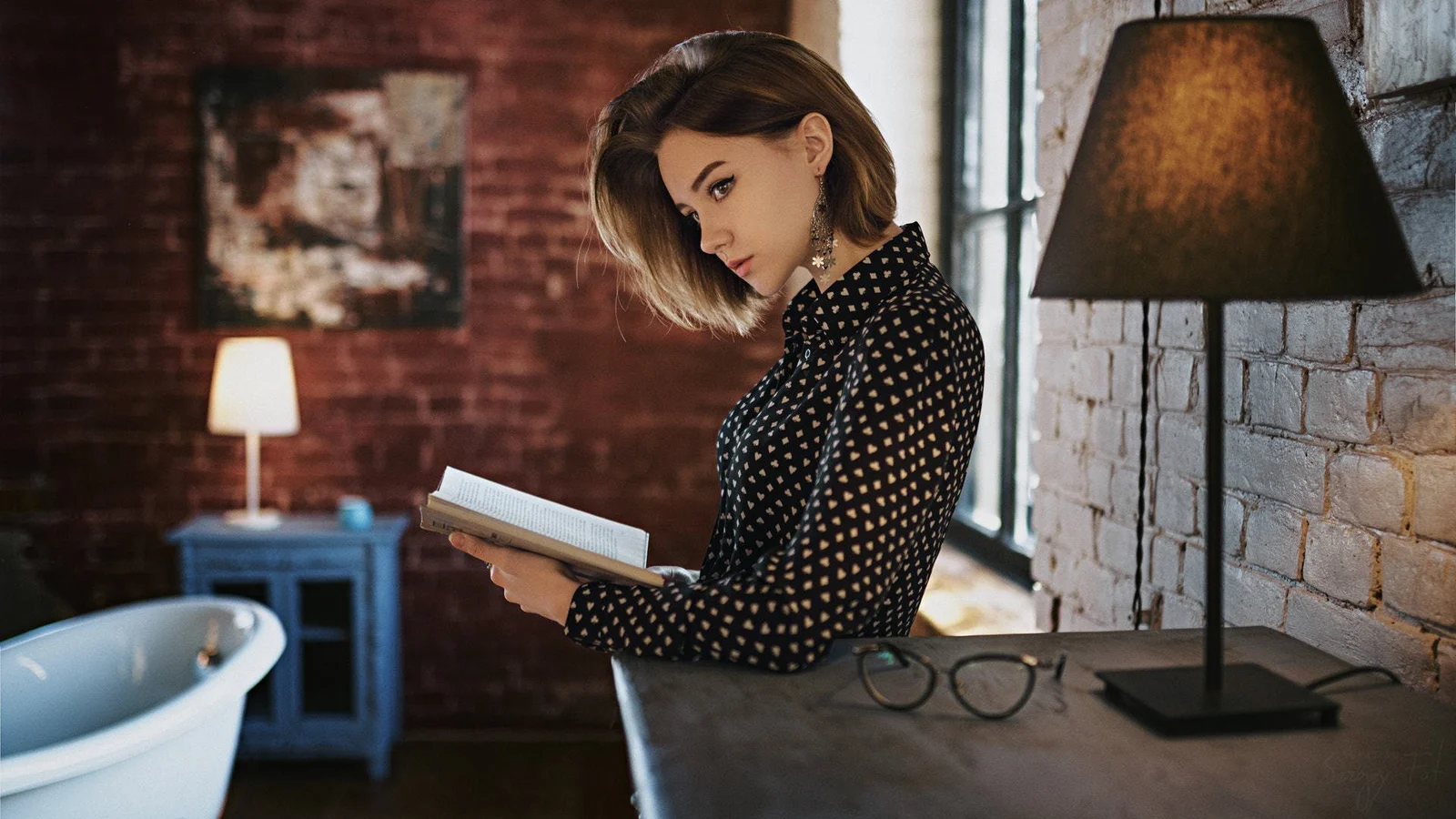 温かみのある室内で成人女性が本を読んでいる。