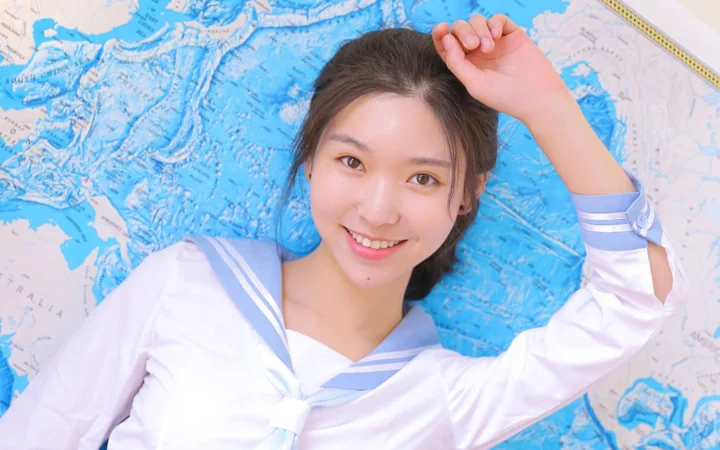 一名身穿白色水手领上衣的女性躺在地图上微笑看向镜头。
