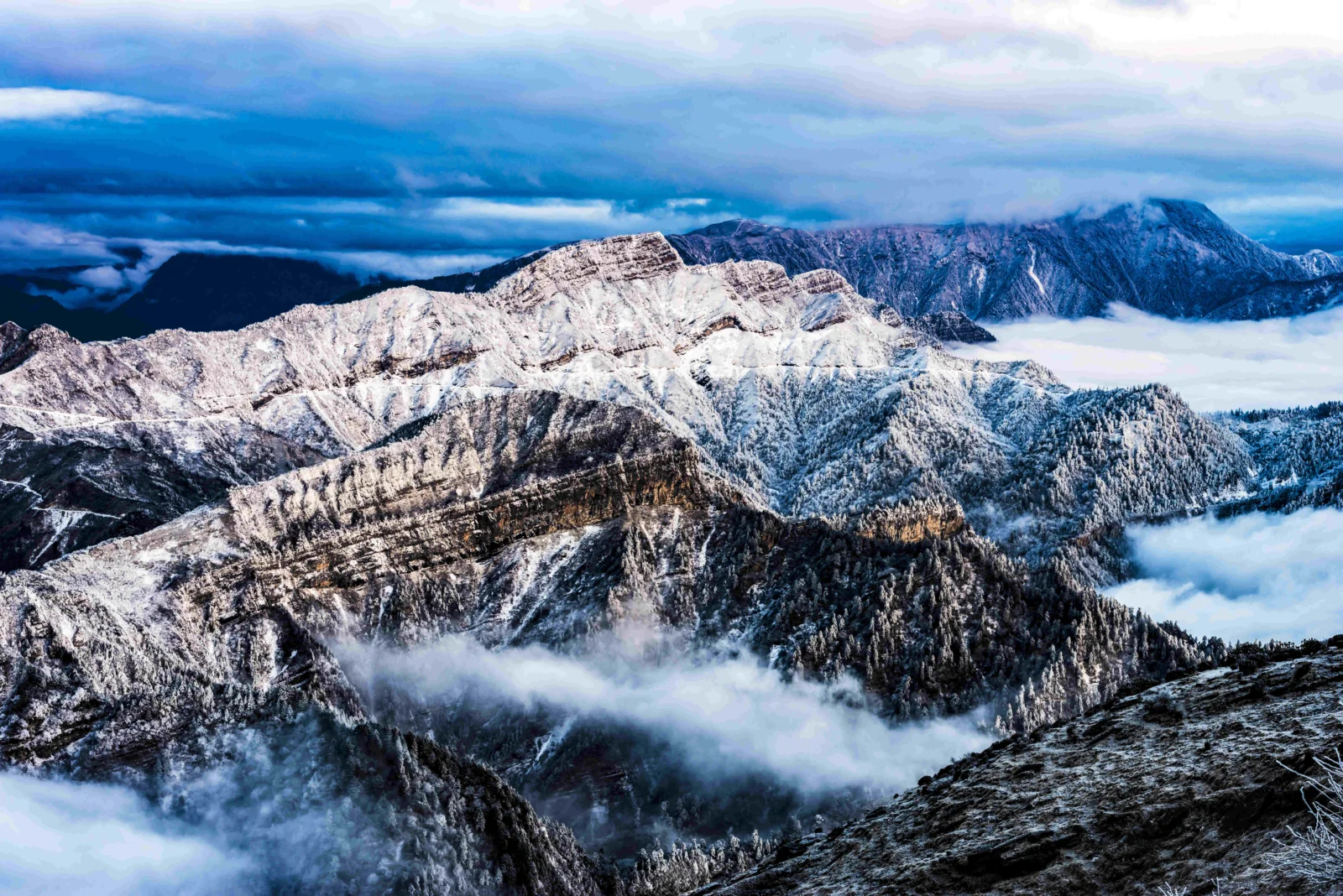 壯麗的雪山、雲霧和深藍色天空構成一幅高山風景畫面。