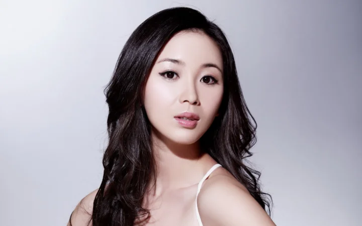 一位黑发女性在浅灰色背景前进行棚拍肖像摄影。