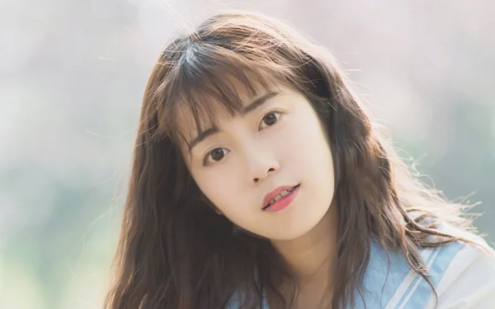 一位长发女性在柔和光线下看向镜头。