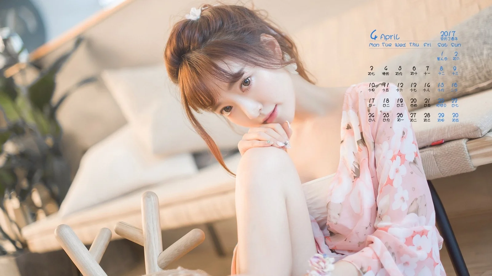 一位成年女性身穿粉色花卉连衣裙坐在室内，画面光线柔和。