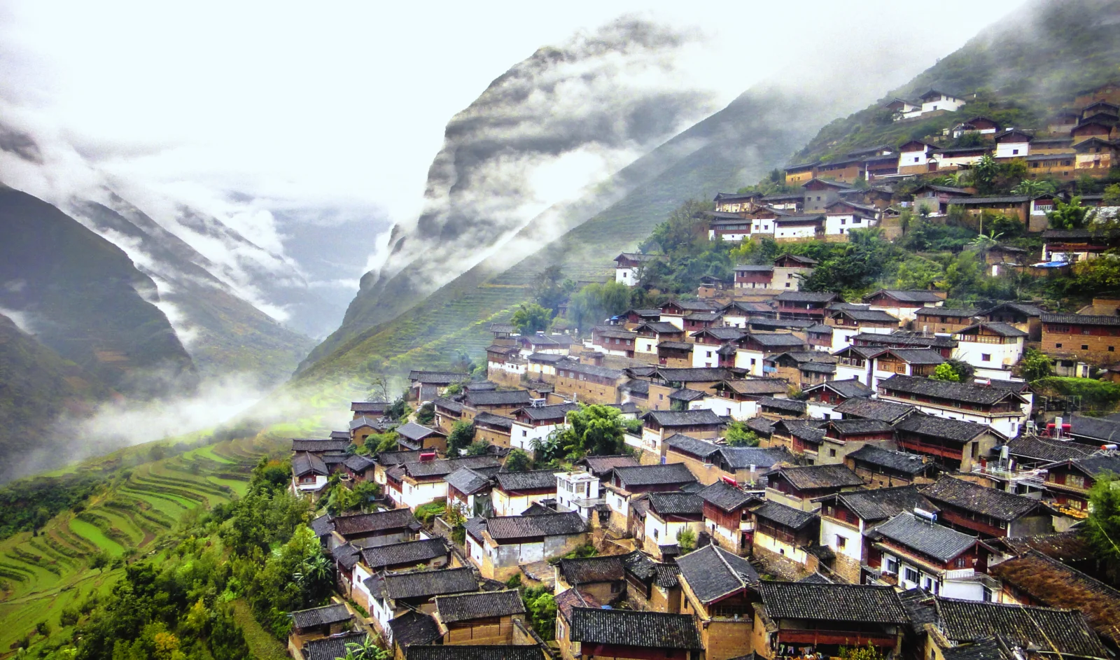 云雾缭绕的高山村落坐落在层层梯田之间。