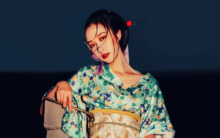 一名成年女子穿着花卉图案服装，在深色背景前摆姿势。