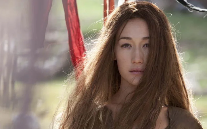 一名长棕发女性在柔和的户外光线下直视镜头。