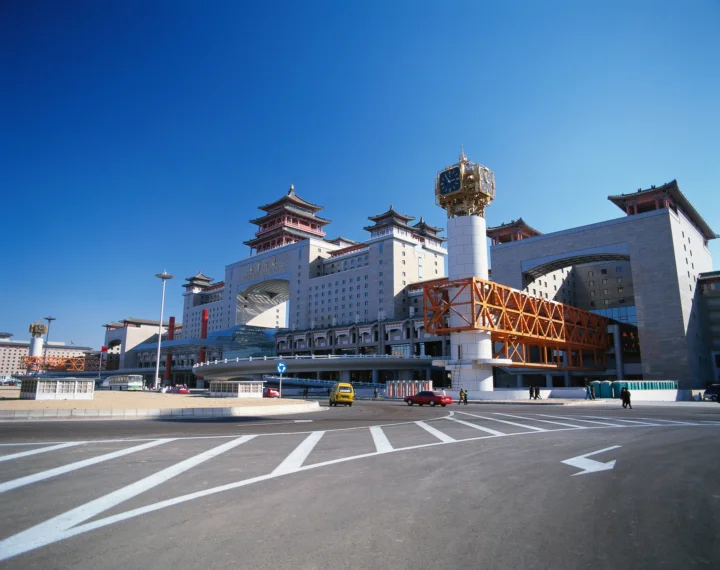 蓝天下，一座大型城市建筑坐落在宽阔道路旁。