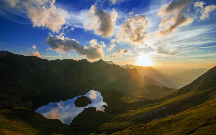 群山环抱的高山湖泊映照着夕阳与绚丽云层。